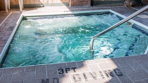 Ein Whirlpool mit Metallleiter, umgeben von einer gefliesten Terrasse, und ein Schild mit der Aufschrift 'NO DIVING'.
