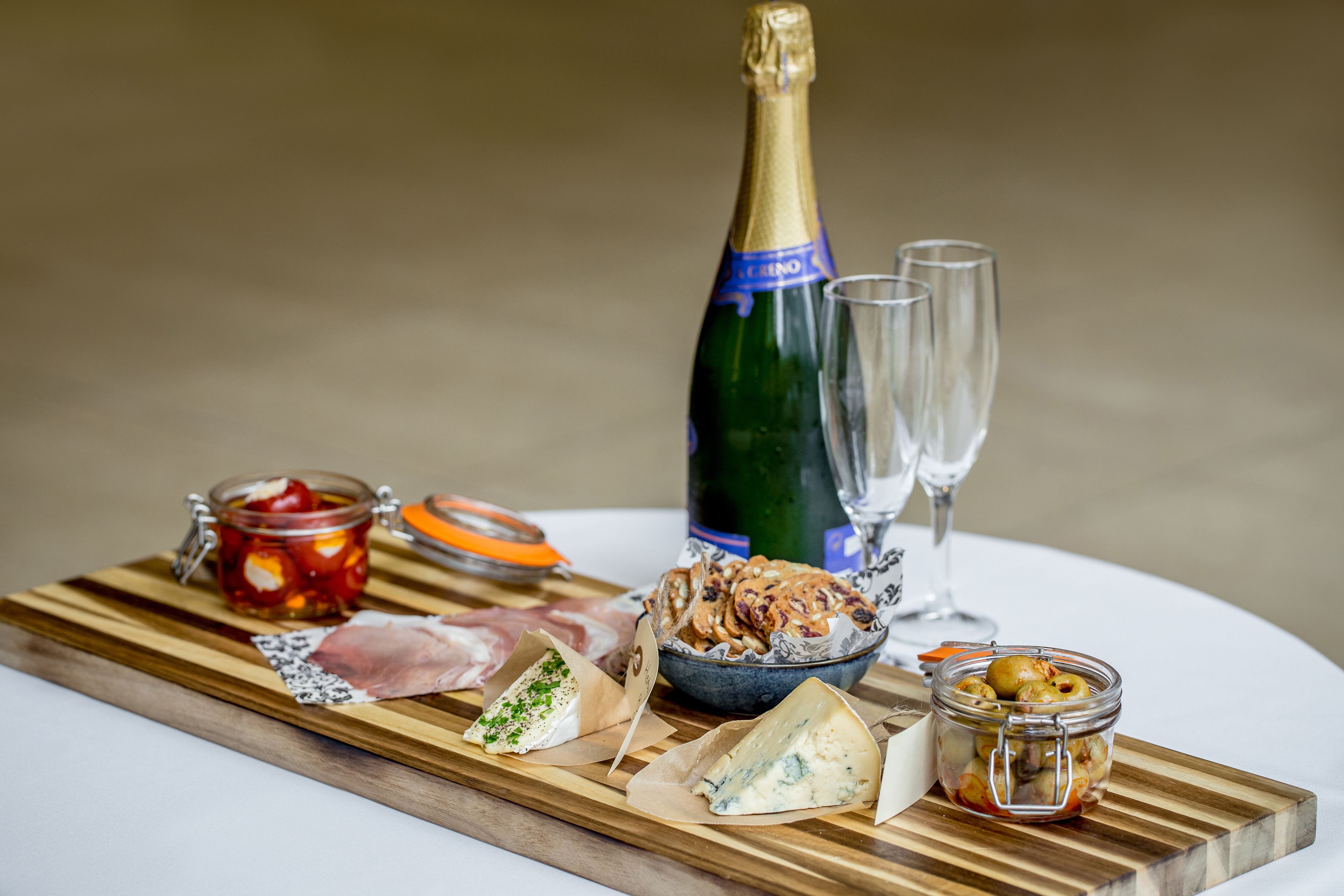 Un tagliere con diversi cibi, una bottiglia di champagne e due calici.