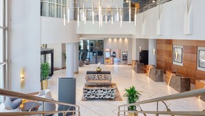 A spacious lobby with a central seating area, a staircase, and a reception desk.