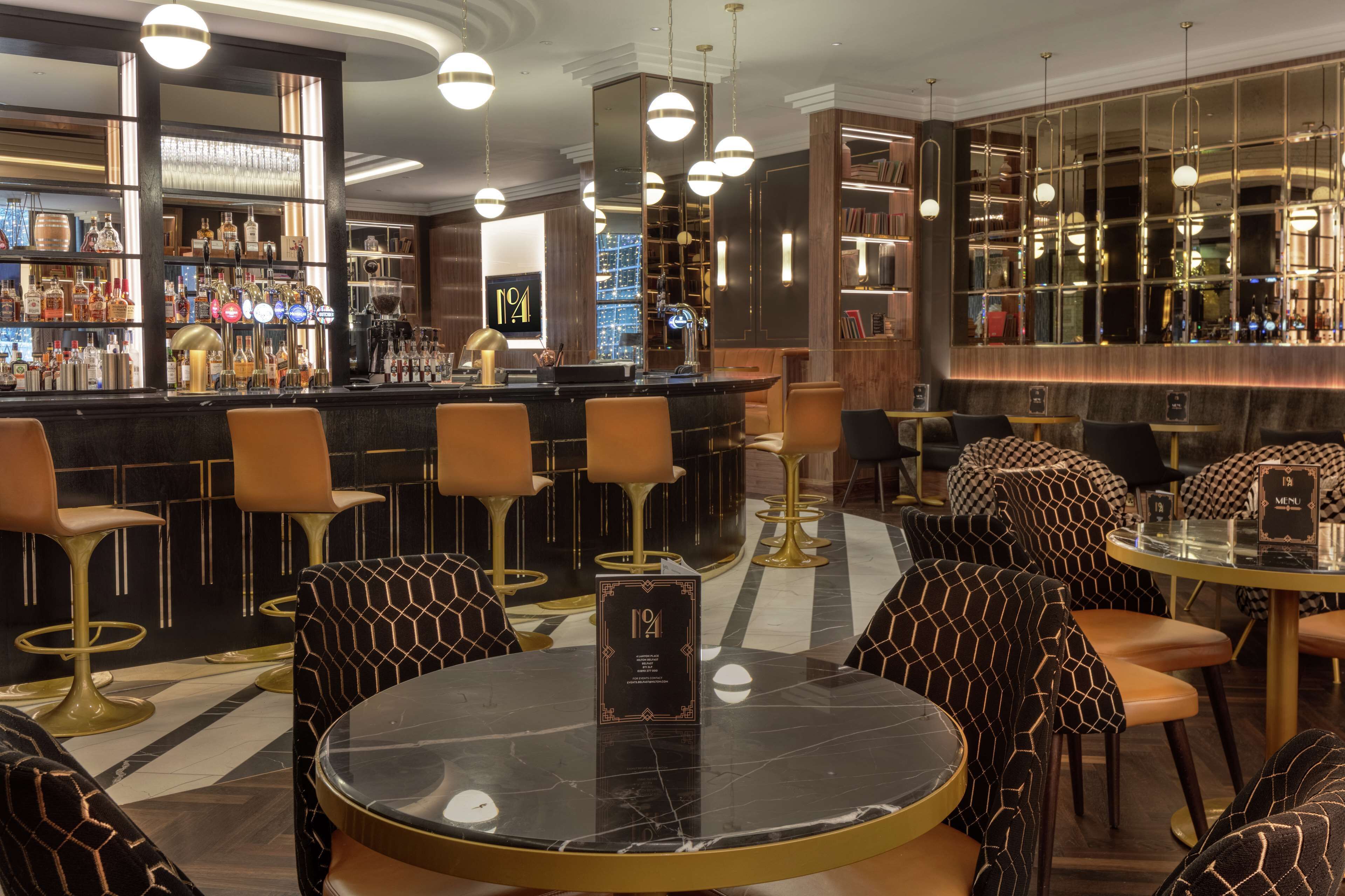 A bar area with a bar counter, multiple stools, and a round table with a menu sign.