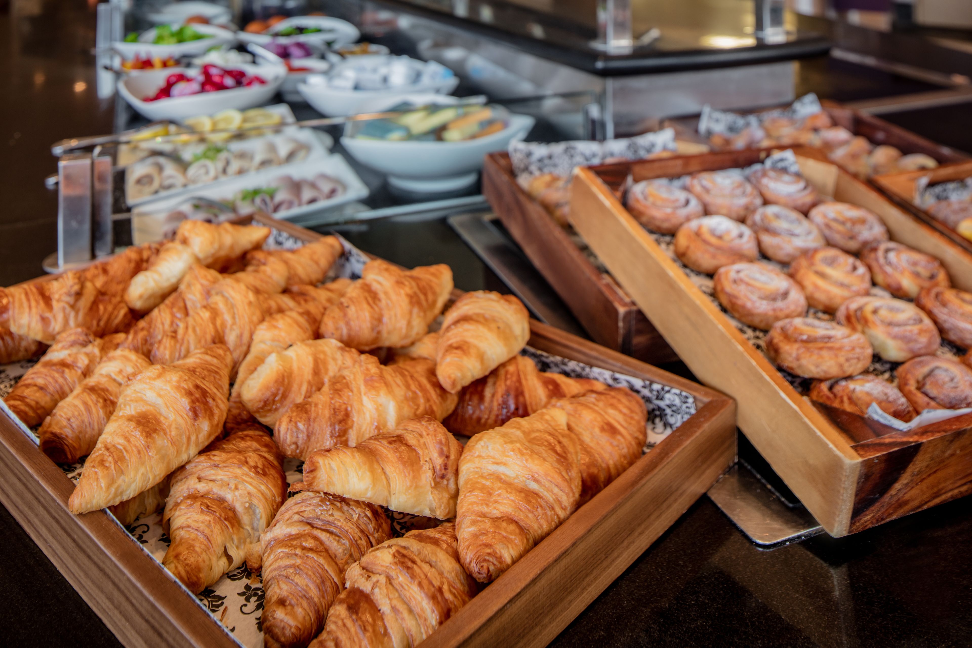 A buffet with various pastries including croissants and cinnamon rolls.