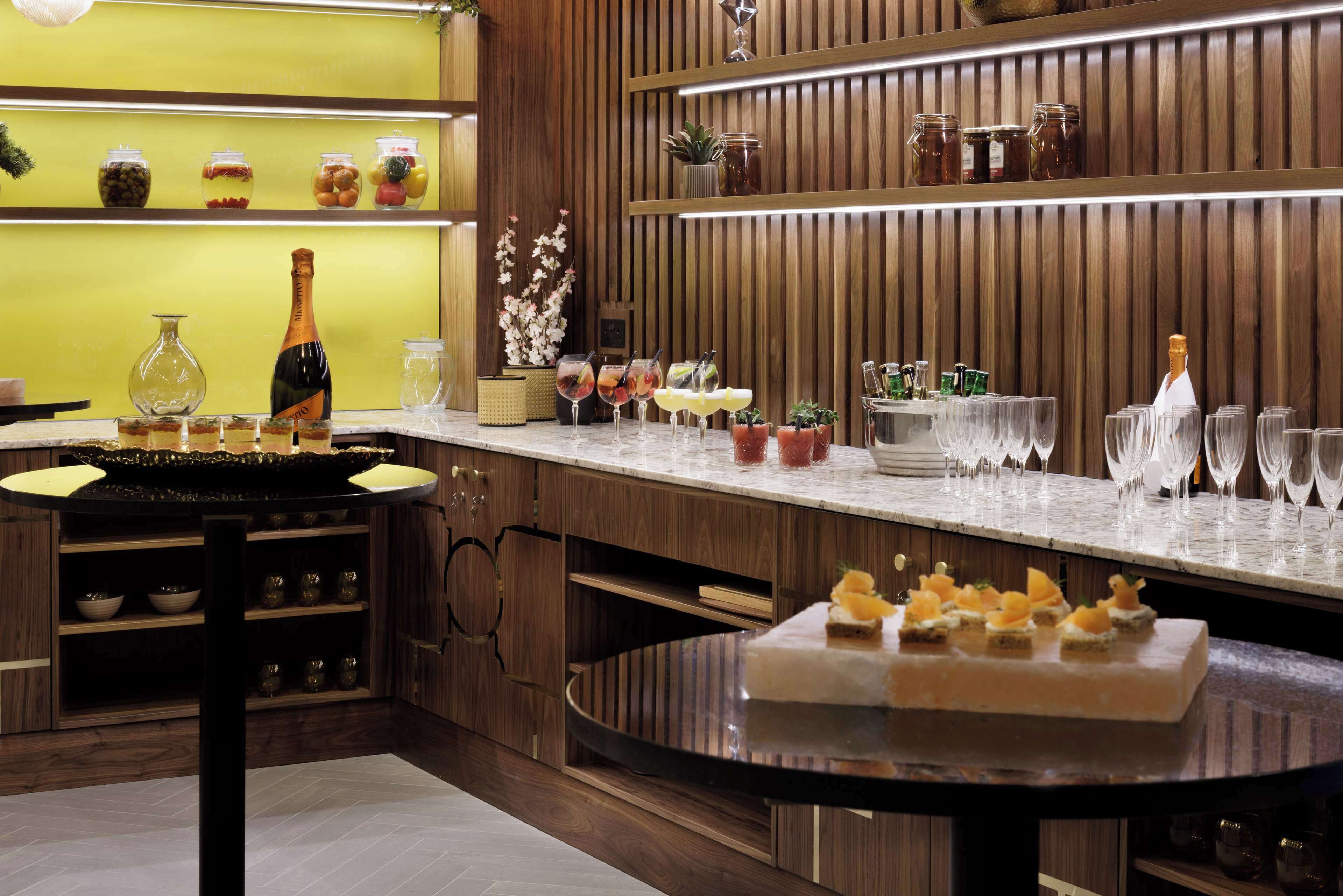 Una cocina moderna con armarios de madera, encimera de mármol y diversos utensilios y objetos decorativos.