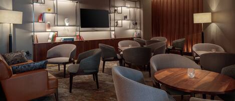A modern living room with a flat-screen TV, multiple seating options, and a wooden coffee table.