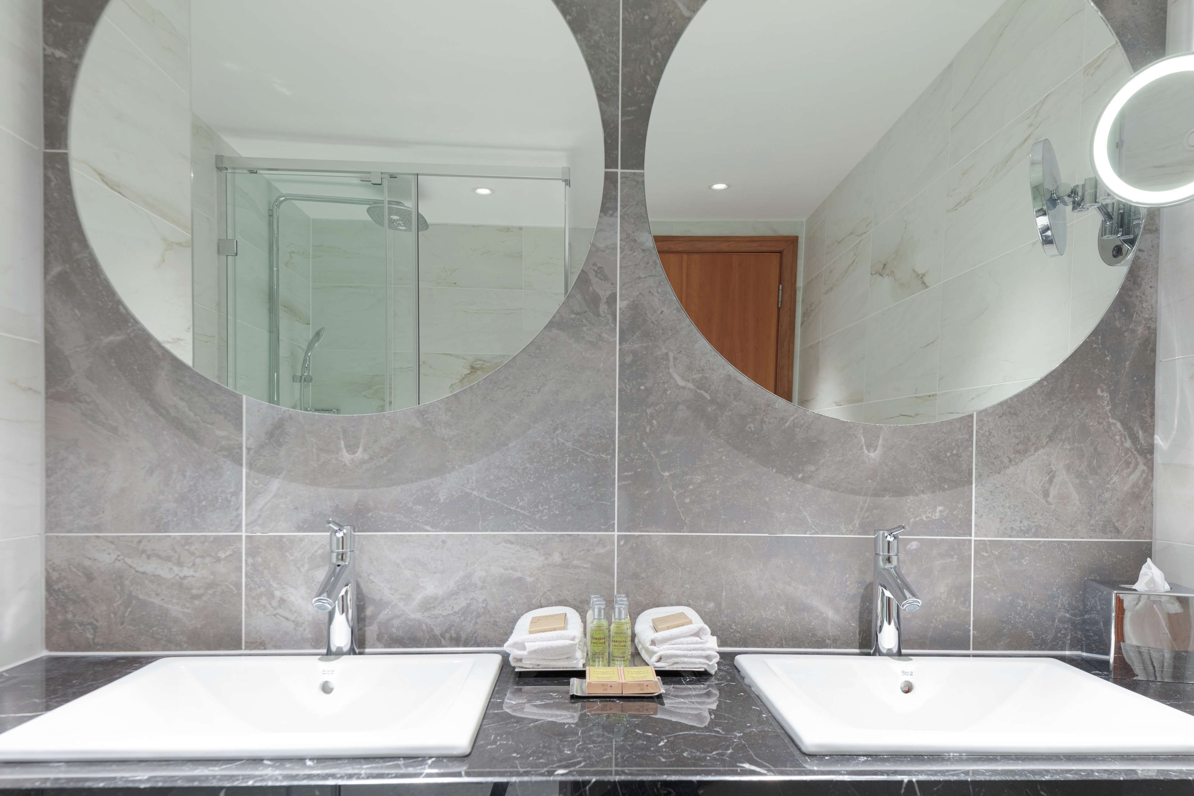 A bathroom with two sinks, a glass shower enclosure, and a wooden door.