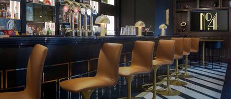 A bar area with multiple stools, a bar counter, and shelves with bottles.