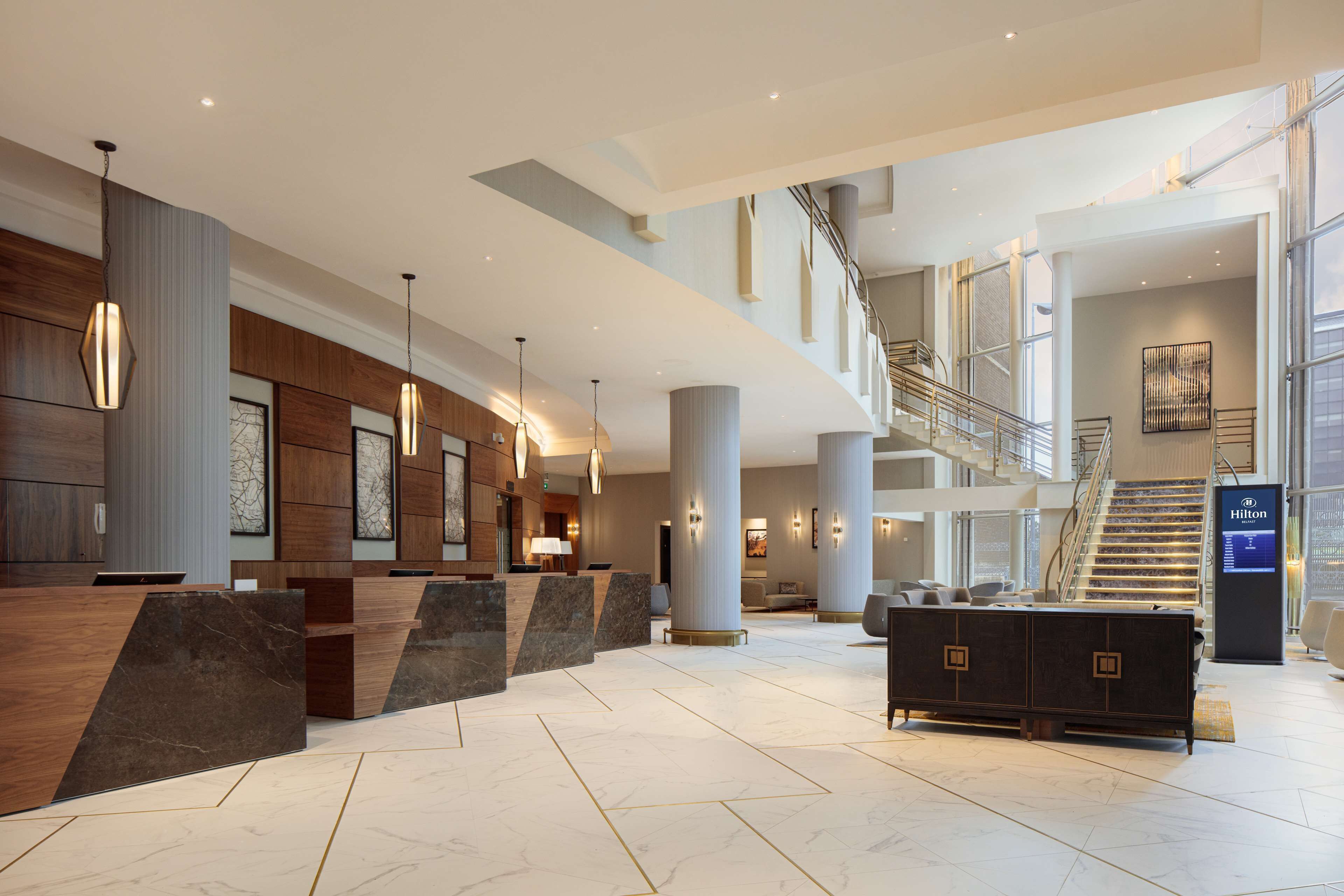 A spacious lobby with a reception desk, seating area, and a staircase leading to upper floors.