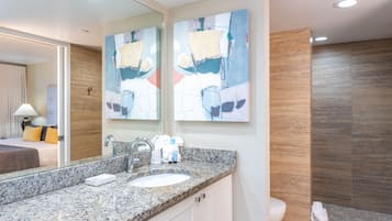 Uma casa de banho moderna com bancada de granito, um espelho grande e duas pinturas abstratas.