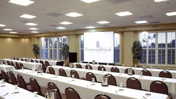 A conference room with rows of tables, chairs, and a projection screen displaying 'Diamond Head beach resort & spa'.