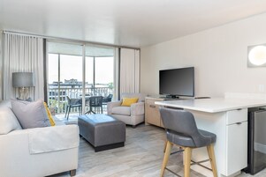 Uma sala de estar moderna com um sofá, um banquinho e uma área de jantar com balcão.