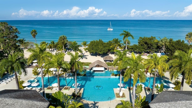 A resort with a swimming pool, palm trees, and a beach. - Couples Negril All Inclusive (Negril)