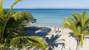 A beach with palm trees, a sandy shore, and a clear blue sea. - Couples Negril All Inclusive (Negril)