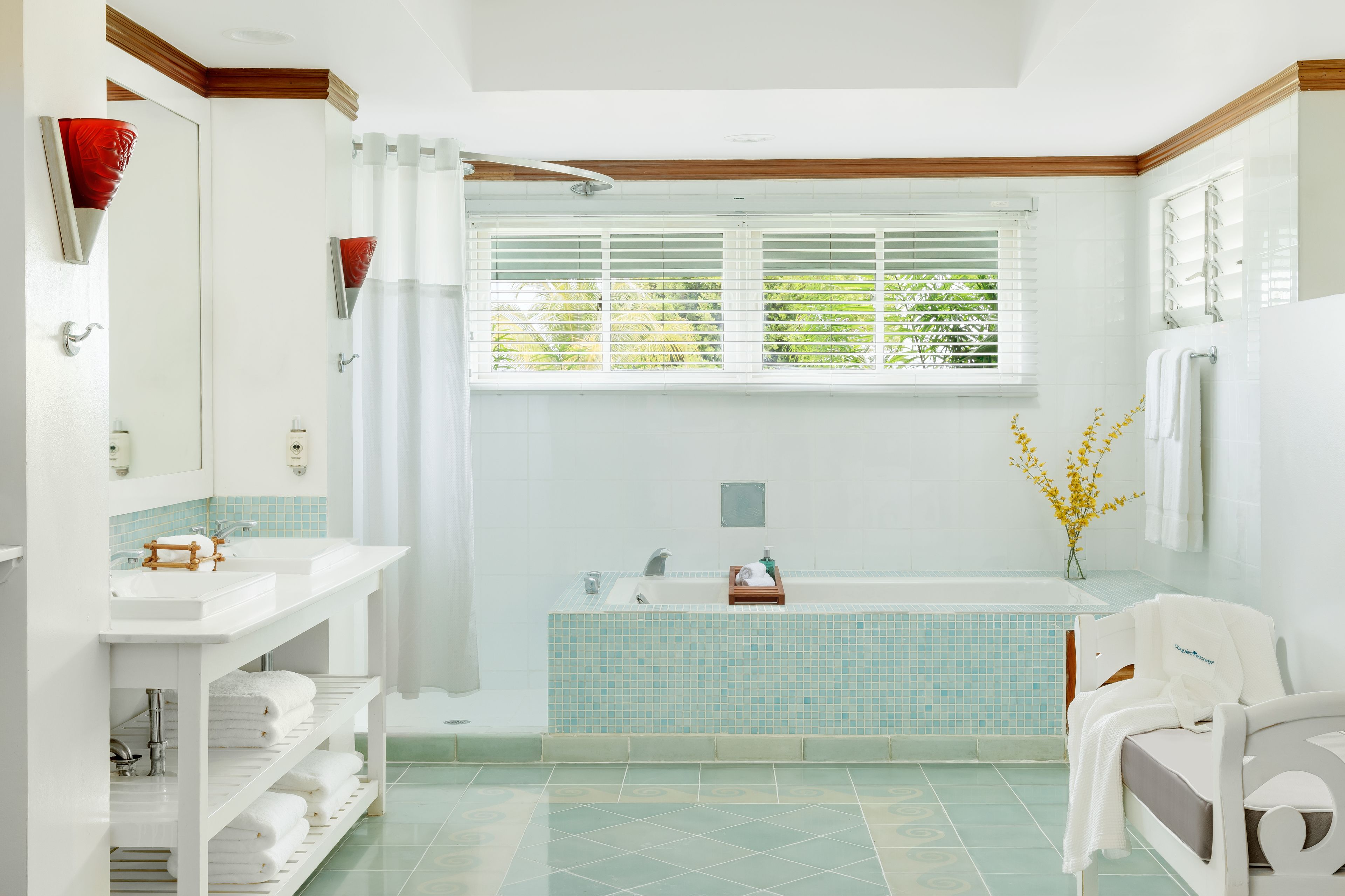 Een moderne badkamer met een bad, een wastafel en een douche. Handdoeken en toiletartikelen liggen op planken.
