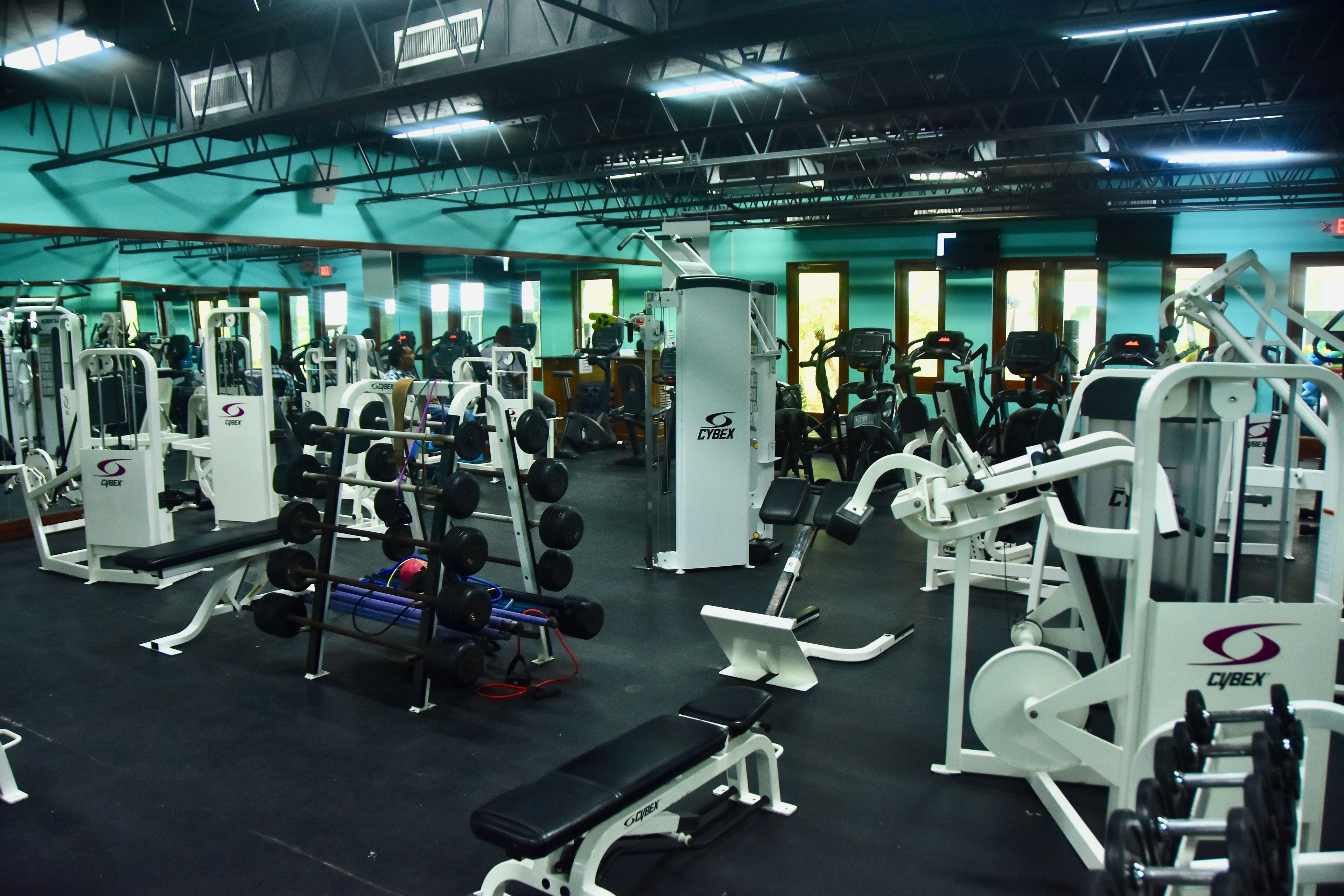 Un gimnasio con diferentes máquinas de ejercicio y pesas.