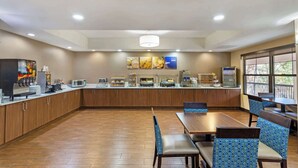 Un comedor amplio con armarios de madera, una barra larga con diversos alimentos y sillas tapizadas en azul.