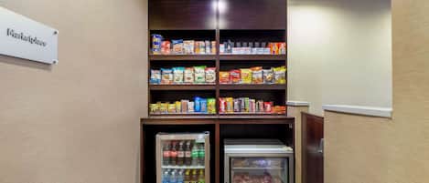 A kitchenette with shelves stocked with snacks, a mini-fridge with beverages, and a freezer.
