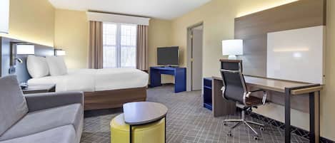 A hotel room with a bed, a desk with a chair, a sofa, and a small table.