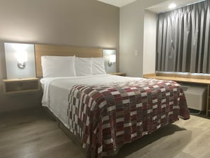 A hotel room with a bed, two bedside tables with lamps, a window with curtains, and a radiator. - Red Roof Inn Winston-Salem (Winston-Salem)