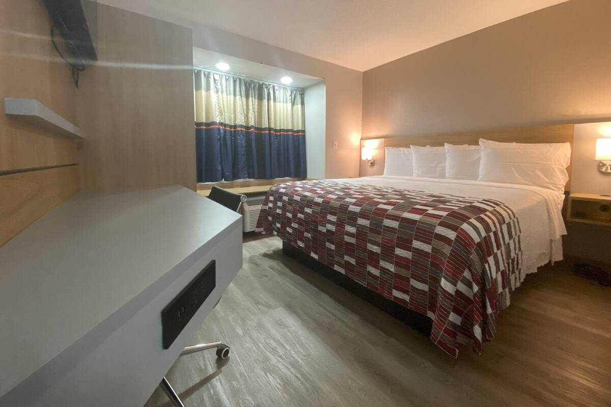 A hotel room with a bed, a desk, and a chair.