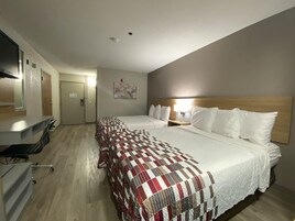 Quarto de hotel com duas camas, uma escrivaninha, uma cadeira e um espelho.