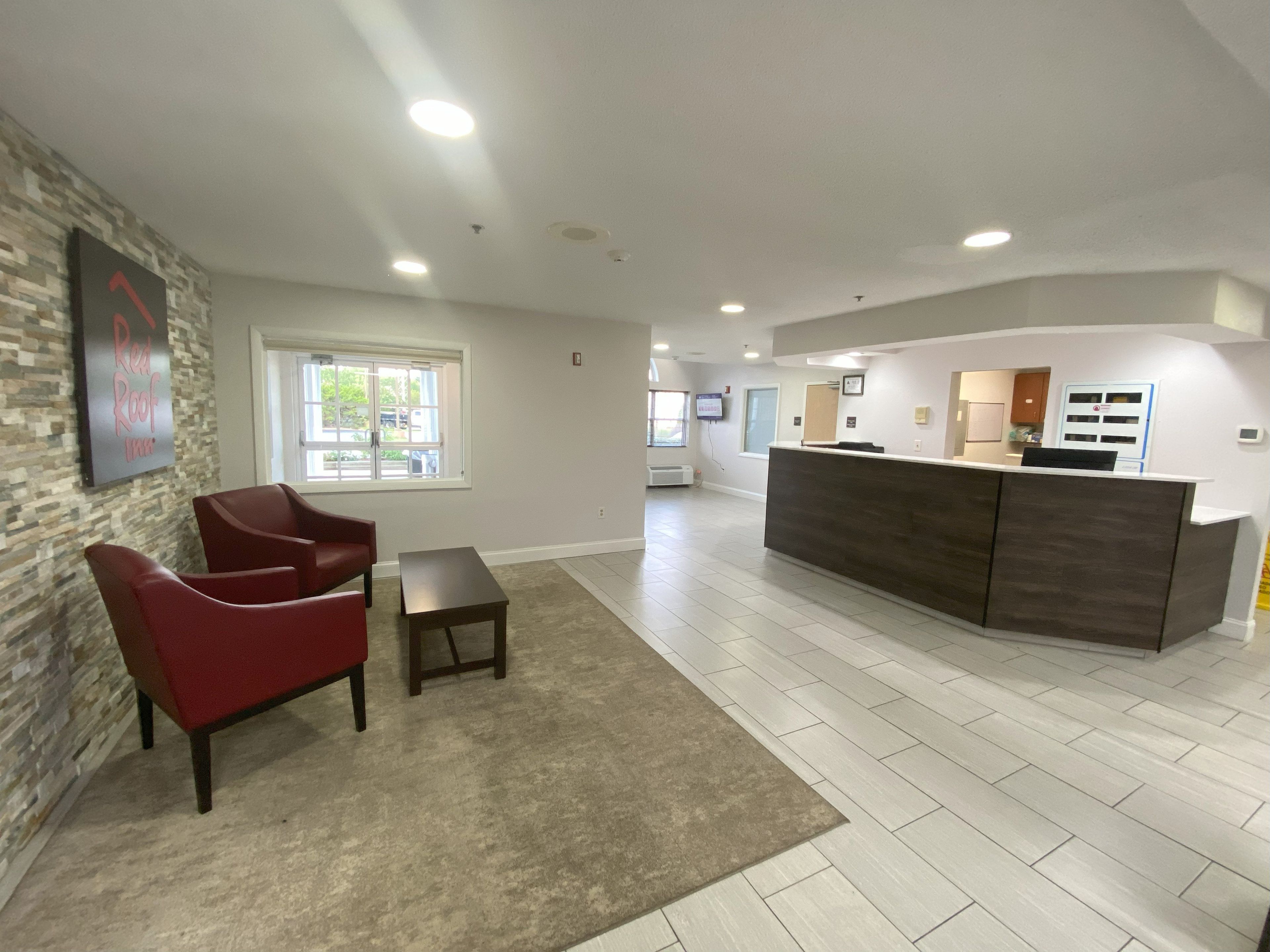 A spacious lobby with a reception desk, a stone accent wall, and a large window providing natural light.