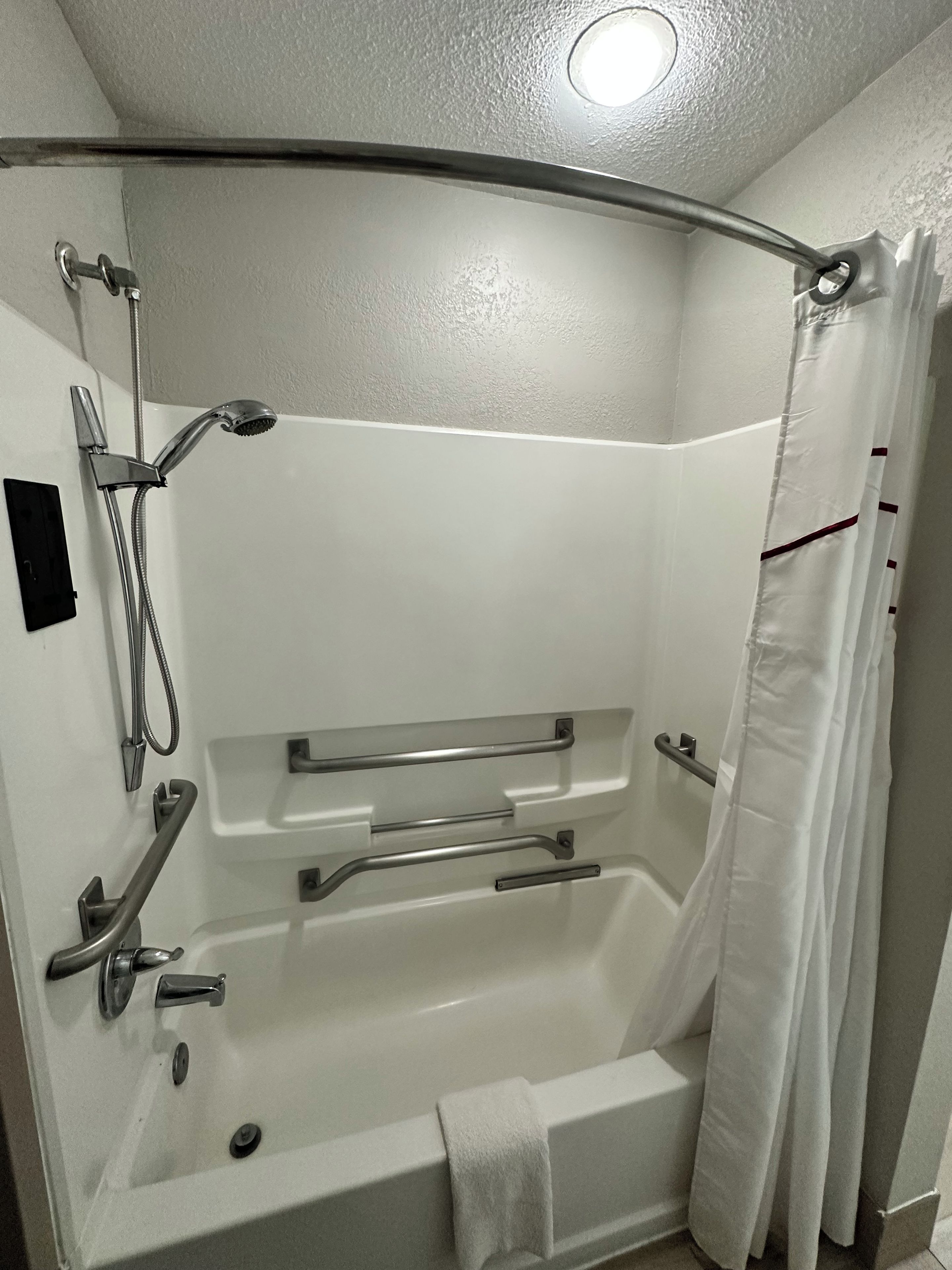 Une salle de bain moderne dotée d’une douche à l’italienne, de barres d’appui et d’un porte-serviettes.