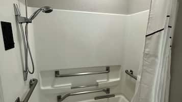 Une salle de bain moderne dotée d’une douche à l’italienne, de barres d’appui et d’un porte-serviettes.