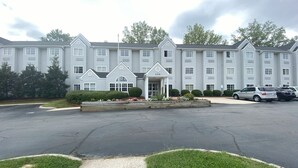 A multi-story hotel with a central entrance, parking area, and surrounding greenery. - Red Roof Inn Winston-Salem (Winston-Salem)