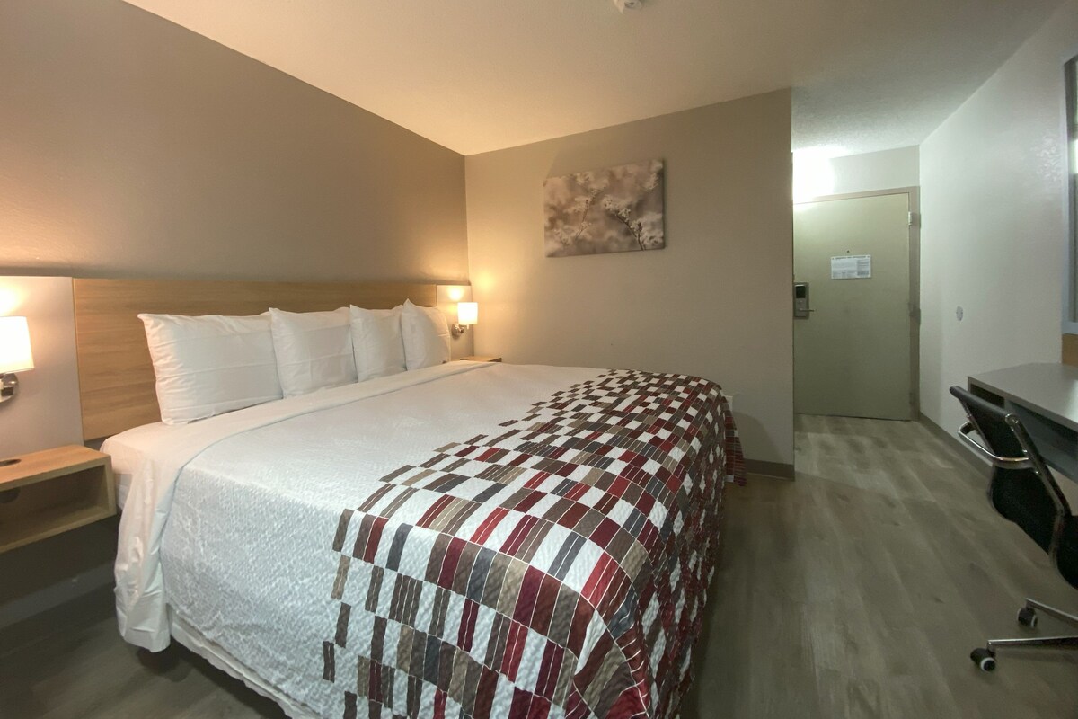 A hotel room with a large bed, a desk, and a chair.