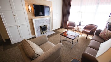 Ein Wohnzimmer mit Kamin, Sofas, einem Couchtisch und einem an der Wand montierten Fernseher.