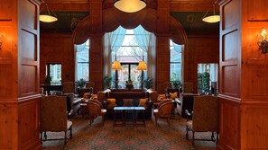 A traditional hotel lobby with wooden paneling, a central seating area, and large windows. - O.Henry Hotel (Greensboro)