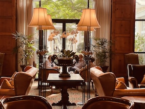 A lobby with leather chairs, a central table with a vase of orchids, and two floor lamps.