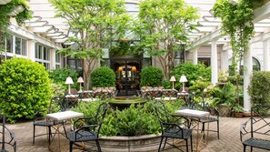 A courtyard with outdoor seating, a fountain, and lush greenery. - O.Henry Hotel (Greensboro)