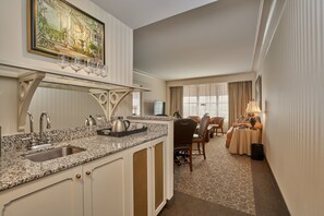 A hotel room with a kitchen area, dining table, and chairs. - O.Henry Hotel (Greensboro)