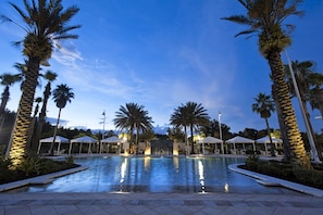 A pool area with palm trees, lounge chairs, and umbrellas. - Monumental Hotel Orlando (Orlando)