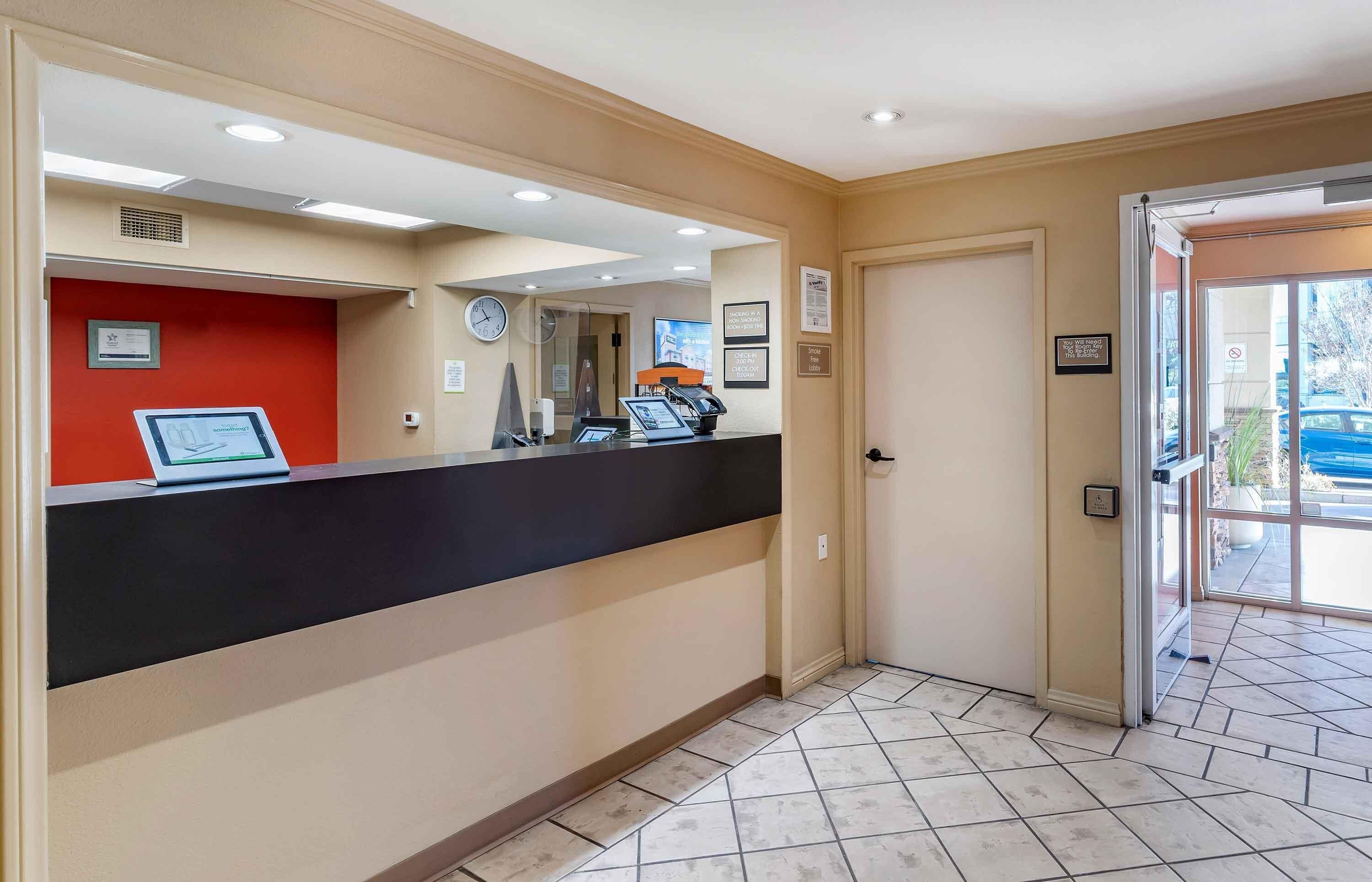 A reception area with a counter, a clock, and a door leading outside.