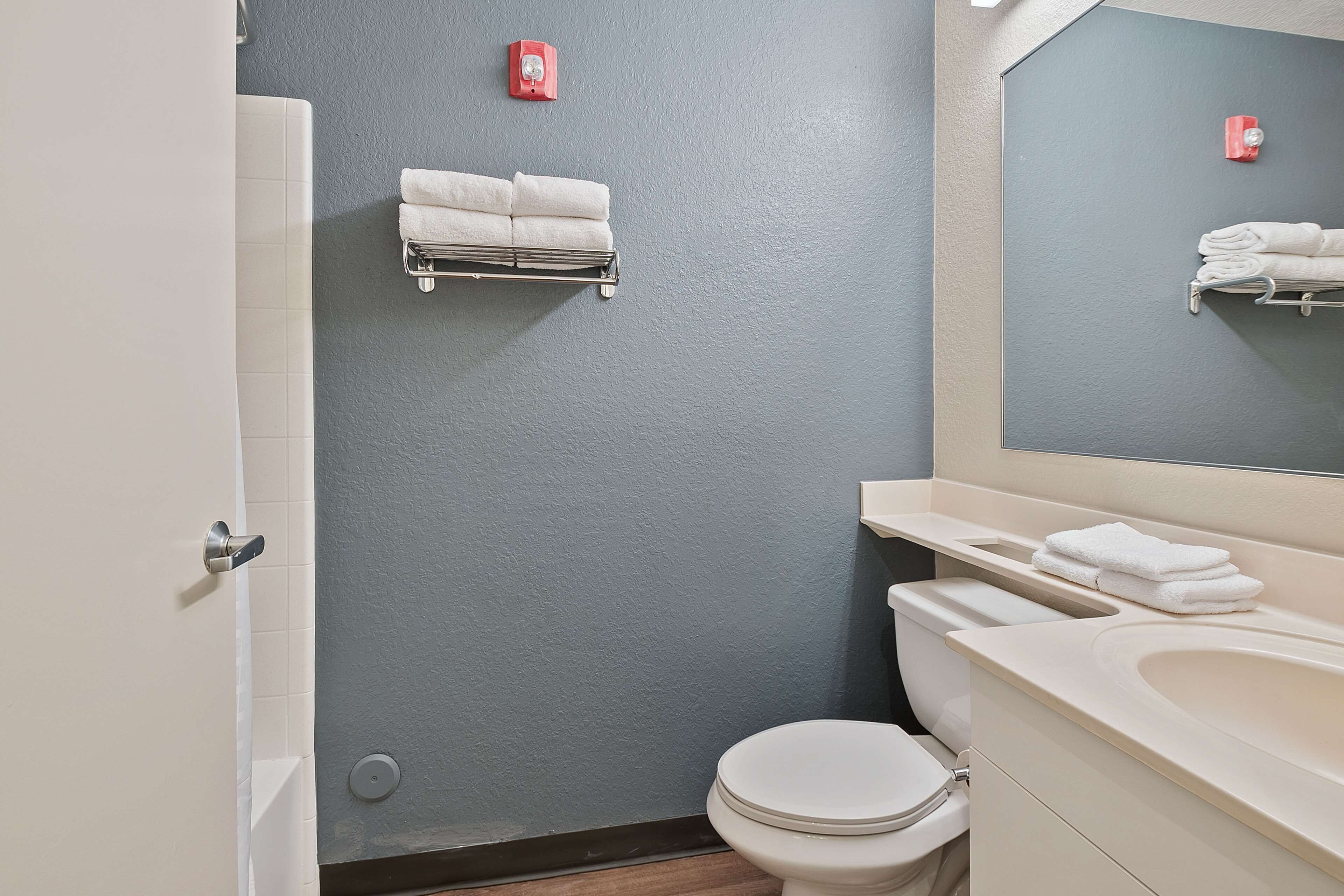 Een badkamer met toilet, wastafel en handdoekhouders.