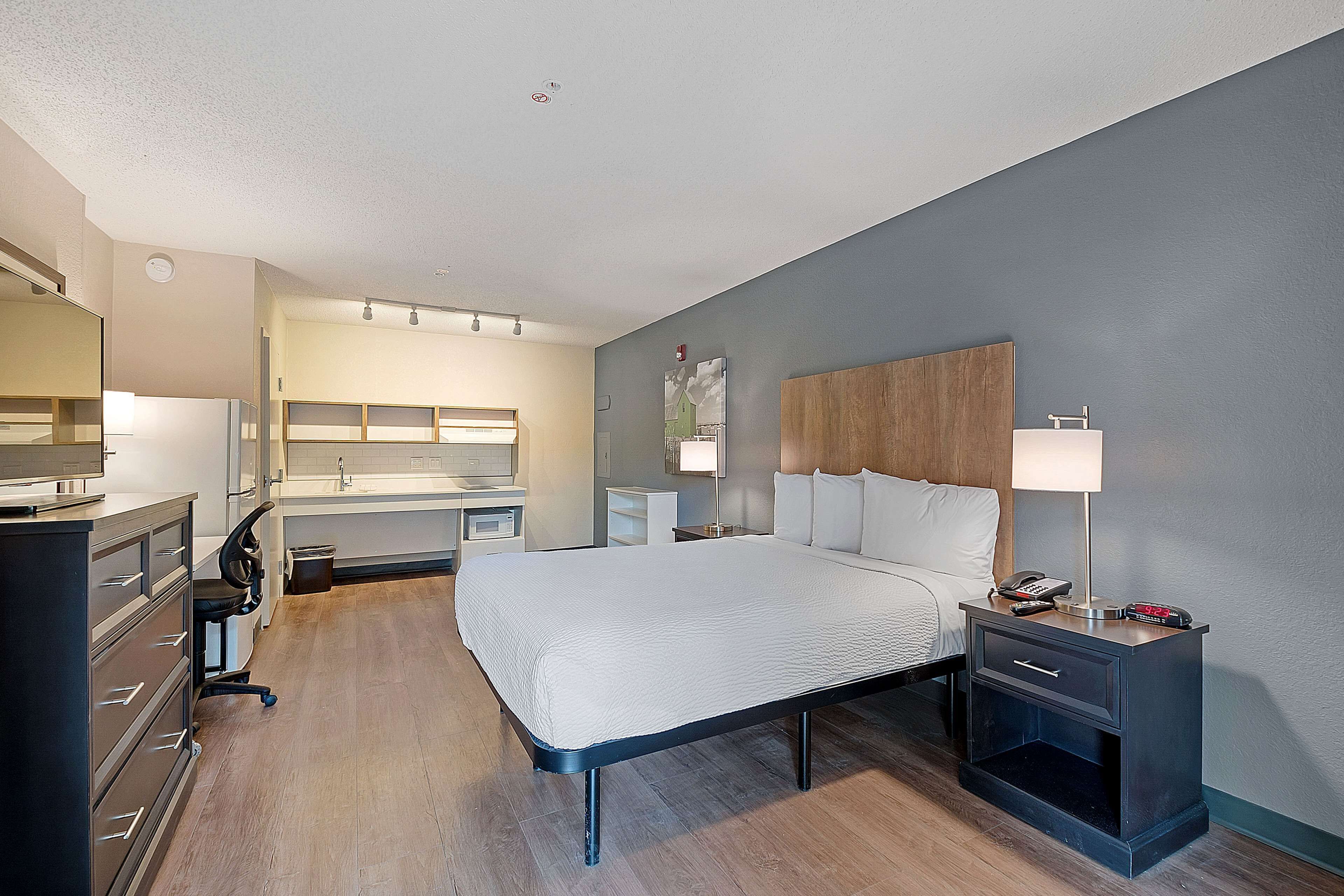 A modern hotel room with a large bed, bedside tables, a desk, and a chair.