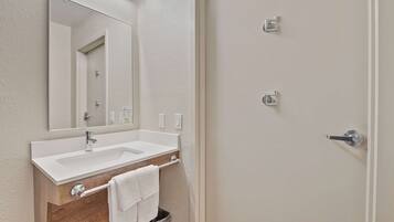 Un bagno con lavandino bianco, specchio e porta asciugamani.