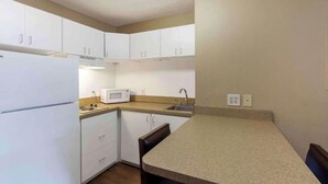 A compact kitchen with white cabinets, a microwave, a sink, and a countertop. - Studio 6 Extended Stay Memphis Airport TN (Memphis)