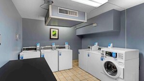 A laundry facility with multiple washing machines and dryers, a tiled floor, and a ventilation system. - Studio 6 Extended Stay Memphis Airport TN (Memphis)