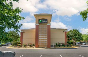 A Stay America hotel with a beige facade, a prominent entrance, and a parking lot. - Extended Stay America Select Suites - Washington, DC - Sterling - Dulles (Sterling)