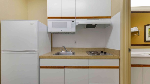 A compact kitchen with a refrigerator, microwave, sink, and cabinets. - Extended Stay America Select Suites - Washington, DC - Sterling - Dulles (Sterling)