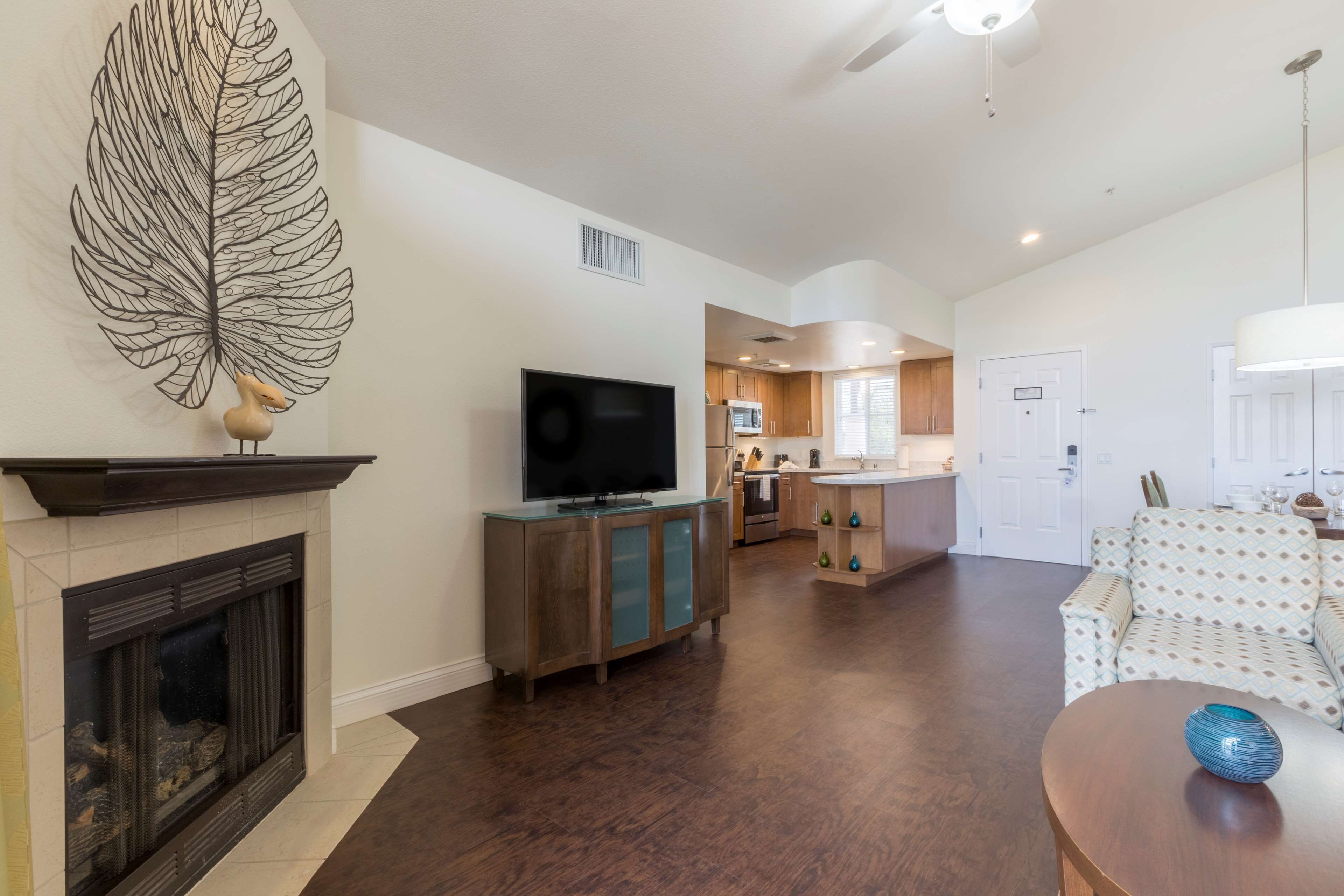 A modern living room with a fireplace, a flat-screen TV, and a dining area with a patterned sofa and a table.