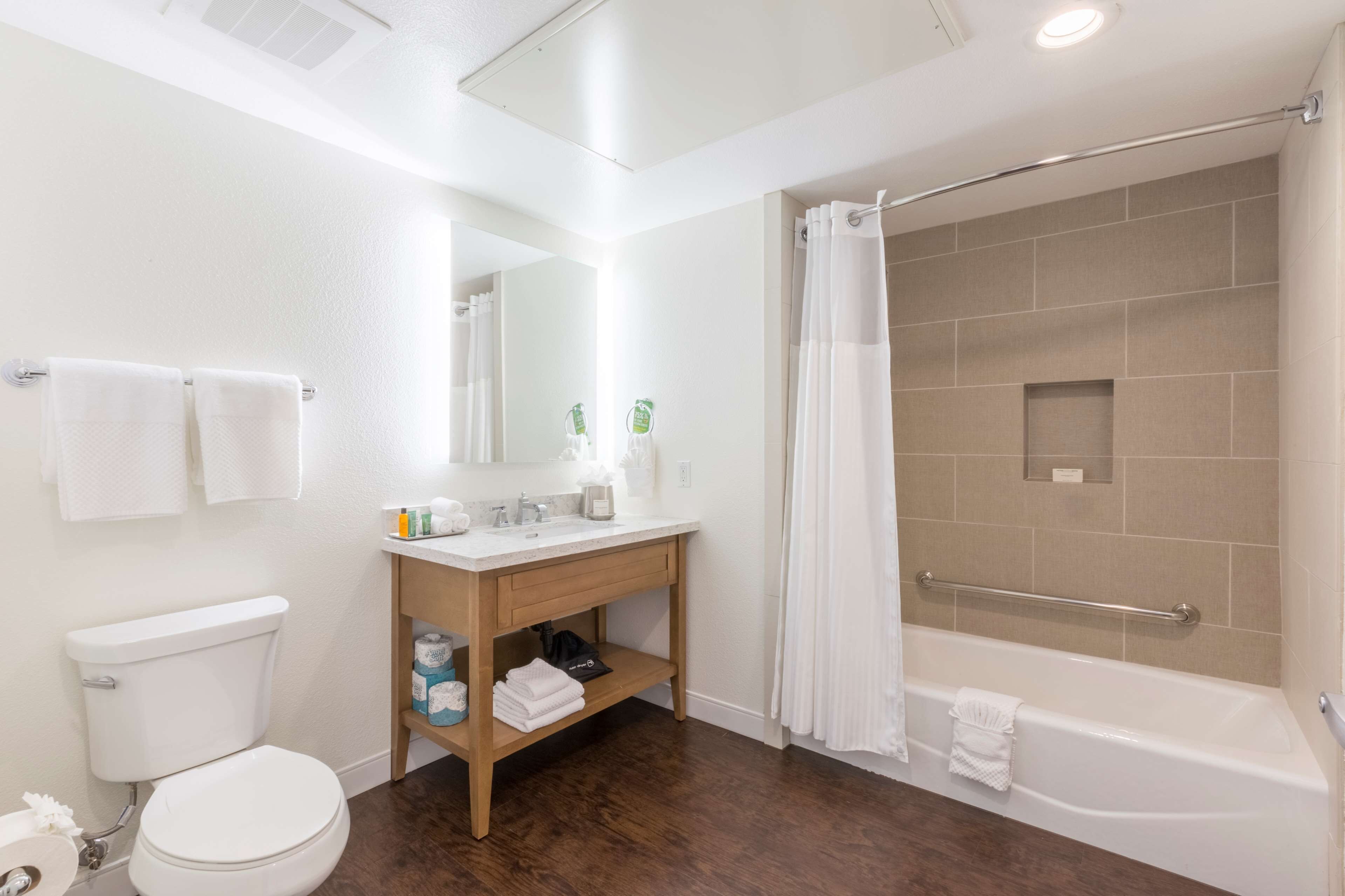 A bathroom with a toilet, sink, vanity, shower, and bathtub.