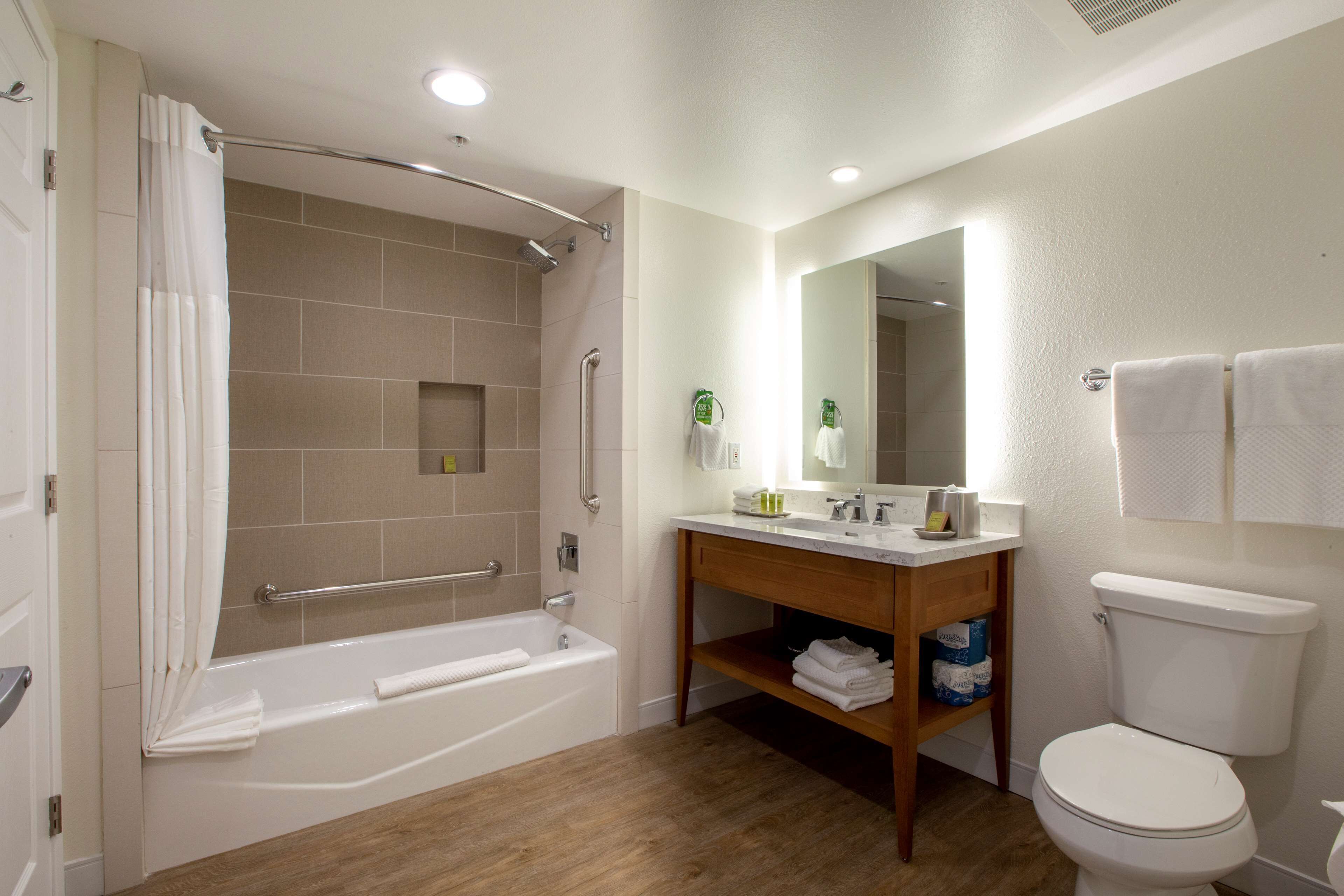 A modern bathroom with a bathtub, toilet, and vanity.