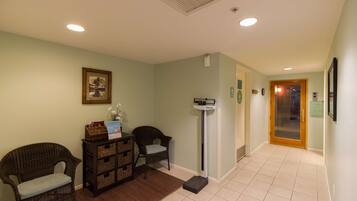A reception area with wicker chairs, a reception desk, a scale, and a framed picture on the wall.