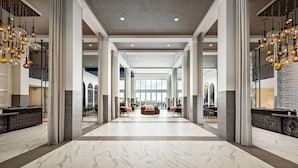 A spacious lobby with marble flooring, a reception desk, and a seating area with sofas and chairs. - Grand Pacific Palisades (Carlsbad)