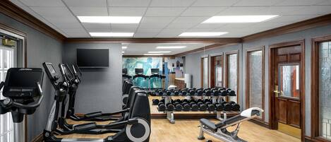 A gym with treadmills, dumbbells, and exercise equipment.