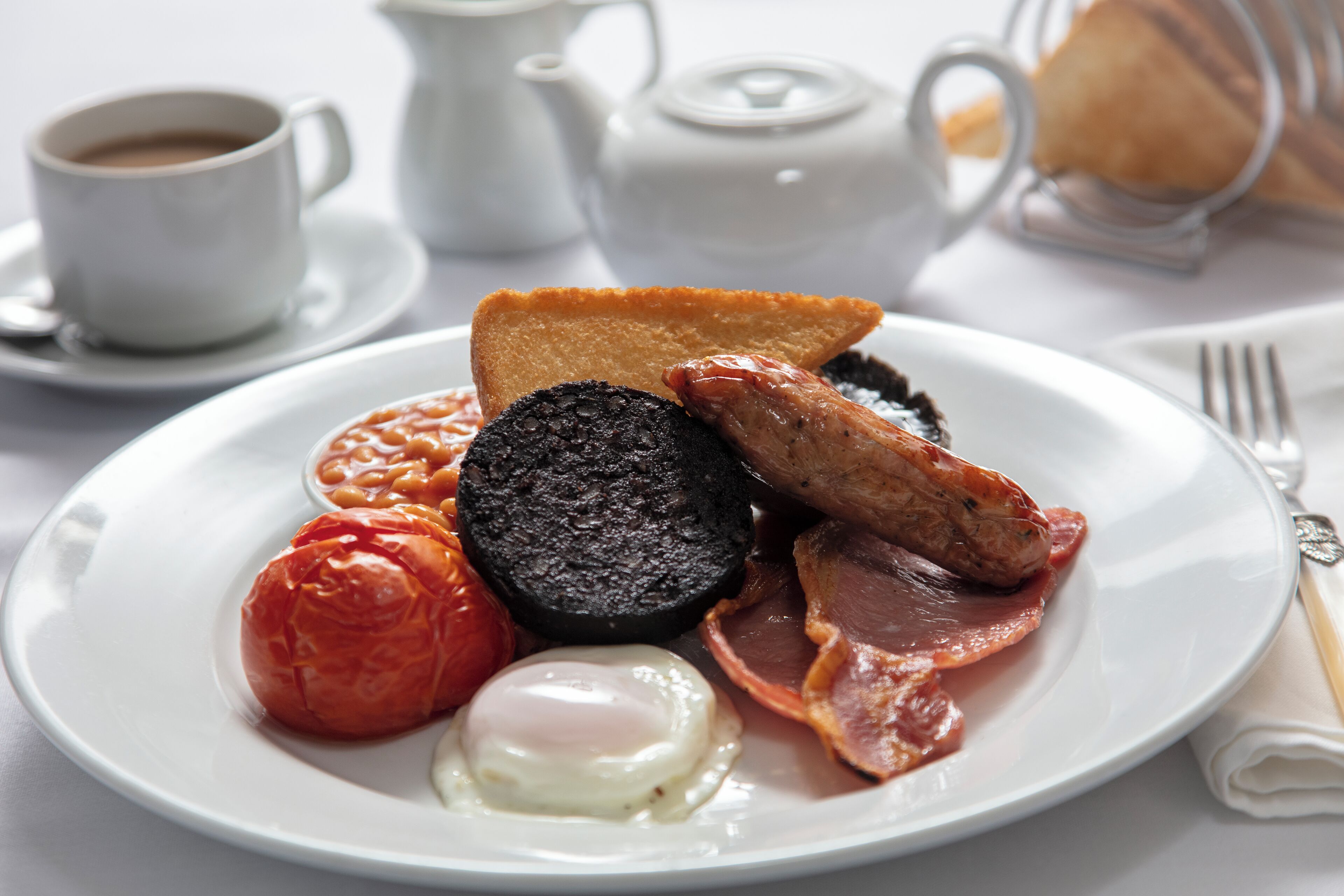 Une assiette de nourriture pour le petit-déjeuner comprenant des œufs, du bacon, des saucisses et des haricots cuits.