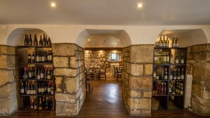 A wine cellar with stone walls and wooden shelves filled with wine bottles. - Hazlewood Castle & Spa (Tadcaster)